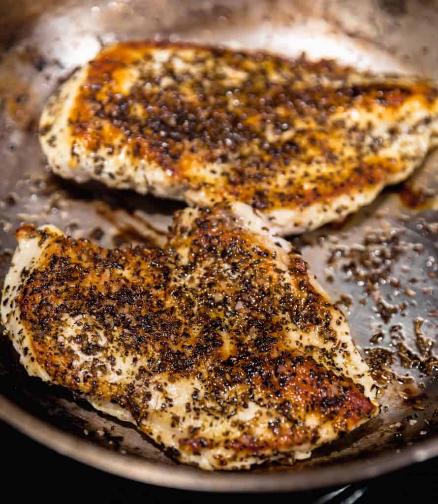 2 chicken breasts with oregano, salt, pepper and dried basil seared to a dark golden brown in a medium sized skillet