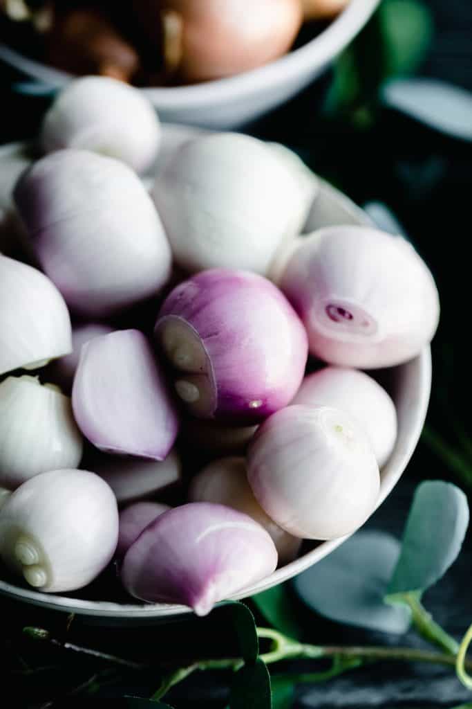a bowl of shallots showing their beautiful purple color against a black background