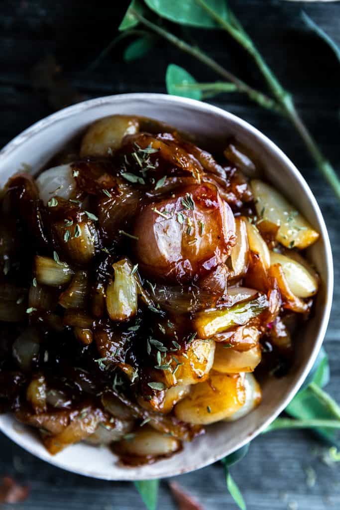 a bowl of glazed shallots sitting on top of a dark surface