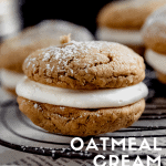 close up of oatmeal cream pies on top of a round cooling rack dusted with powdered sugar