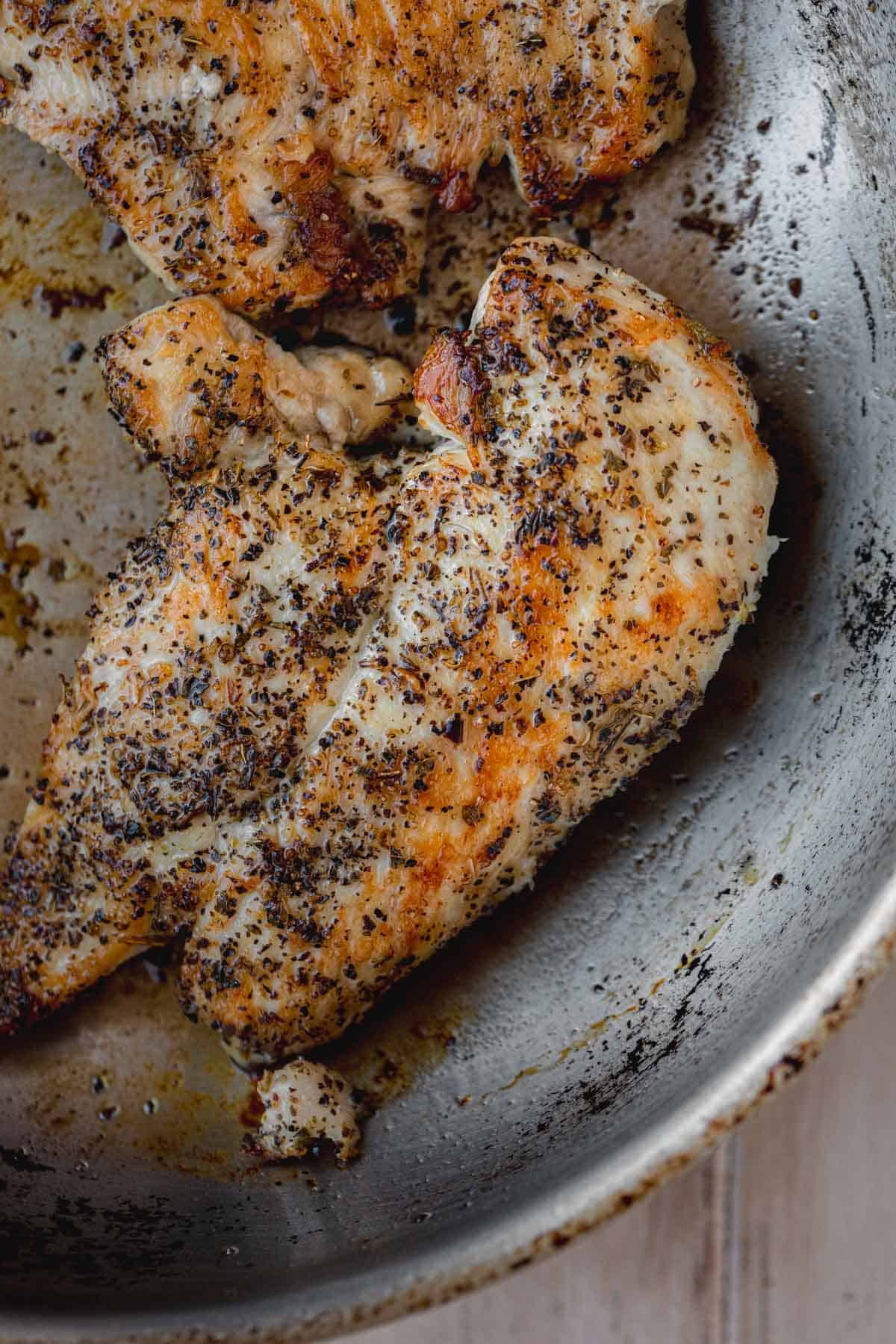Seasoned seared chicken breast in a small skillet. 