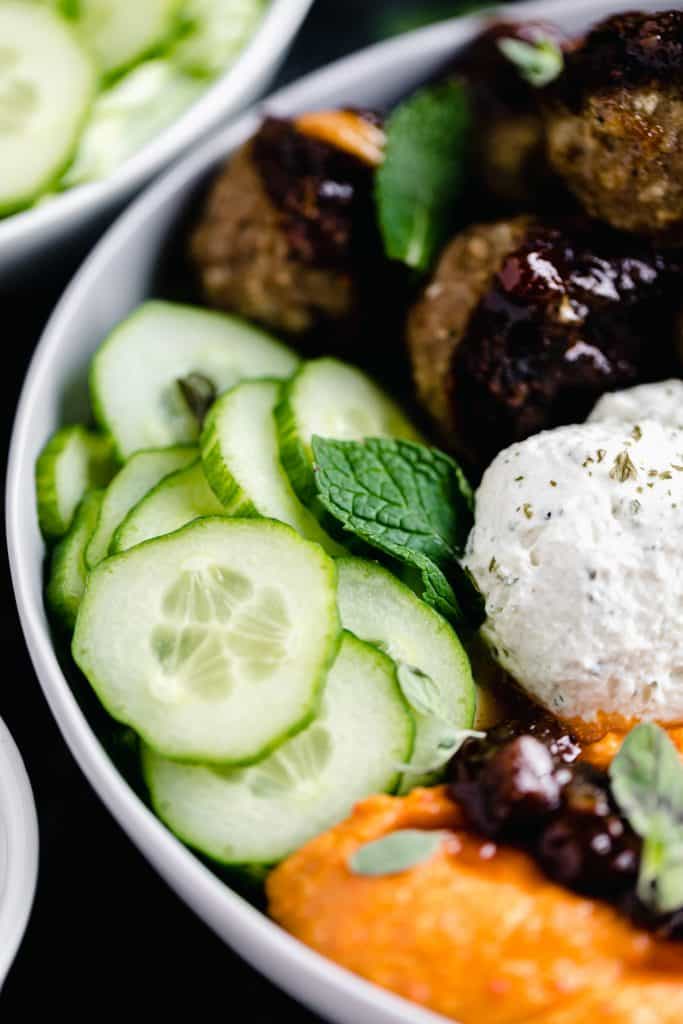 close up of the Mediterranean Bowl with all of the cucumber, garlic cheese spread, meatballs, lemon chutney, cherry pepper hummus and fresh mint and oregano