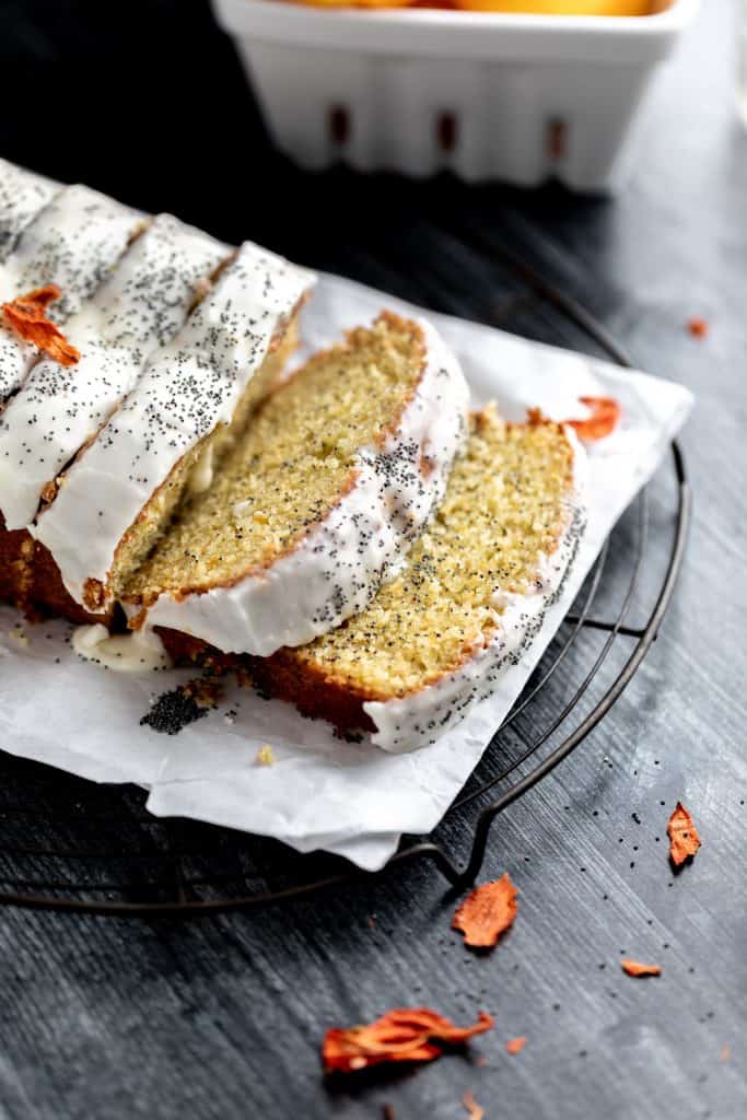 sliced orange poppy seed bread with 2 slices laying flat so you can see the inside of the bread, sitting on a dark wood surface