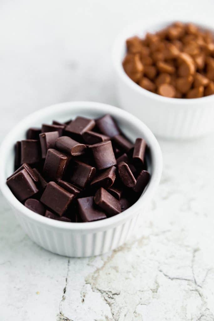 white ramekin full of dark chocolate chunks with a dish of butterscotch chips behind it