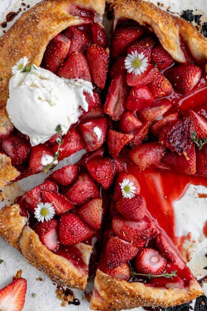 close up overhead shot of the strawberry galette after it is baked topped with honey vanilla ice cream and daisies