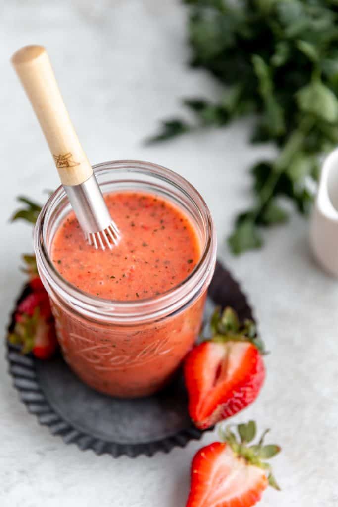 a jar of strawberry vinaigrette with a small whisk inside of it