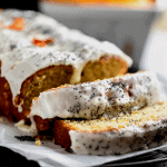 sliced orange poppy seed bread topped with a yogurt glaze, poppy seeds and dried orange flowers