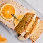 orange poppy seed bread with slices of fresh orange and thyme on top with a few slices lying to the side.