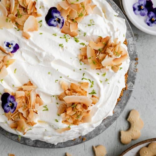 coconut cream pie topped with toasted coconut flakes and purple flowers