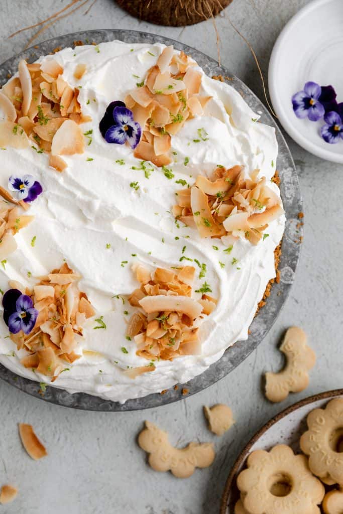 coconut cream pie topped with toasted coconut flakes and purple flowers