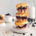Blueberry Streusel Muffins stacked on top of each other on a plate.