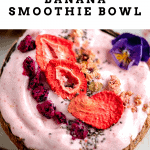 close up shot of a strawberry banana smoothie bowl topped with freeze dried strawberries, dragon fruit and granola