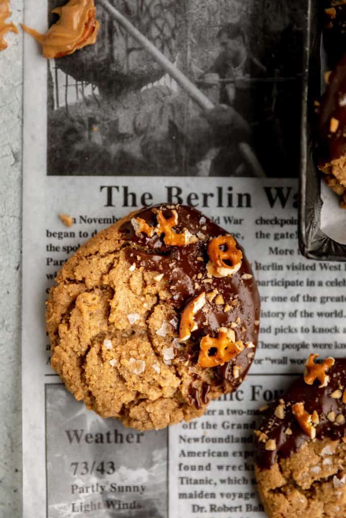 peanut butter cookies dipped in chocolate set on a newspaper deli sheet