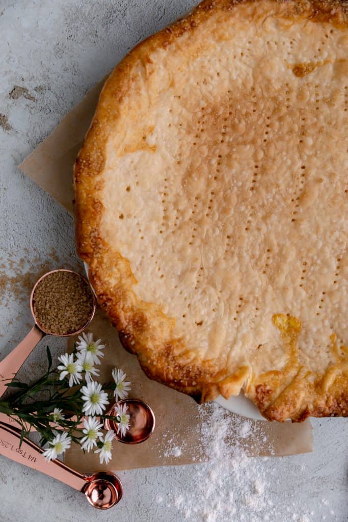 pie crust with flowers and measuring spoons next to it