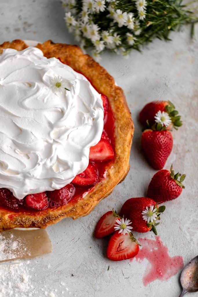 a whole pie with strawberries next to it and white flowers