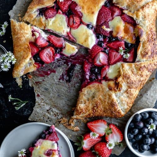 berry cheesecake galette with a slice cut out and set on a stack of plates