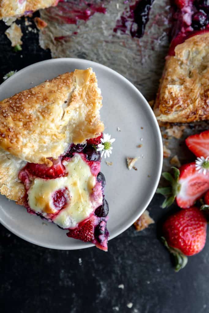 a slice of berry cheesecake galette on a stack of plates