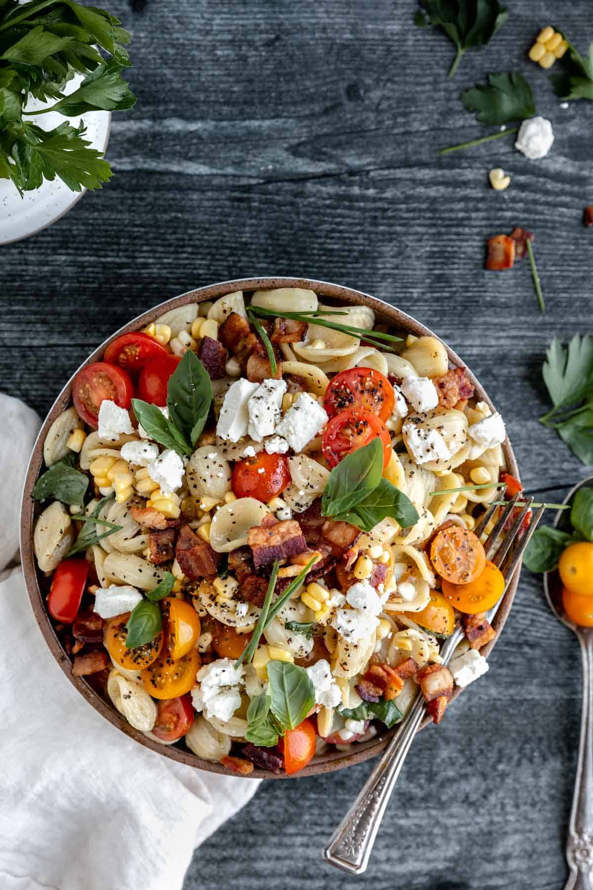 Summer Pasta Salad with tomatoes, corn, bacon, herbs and feta cheese in a bowl. 