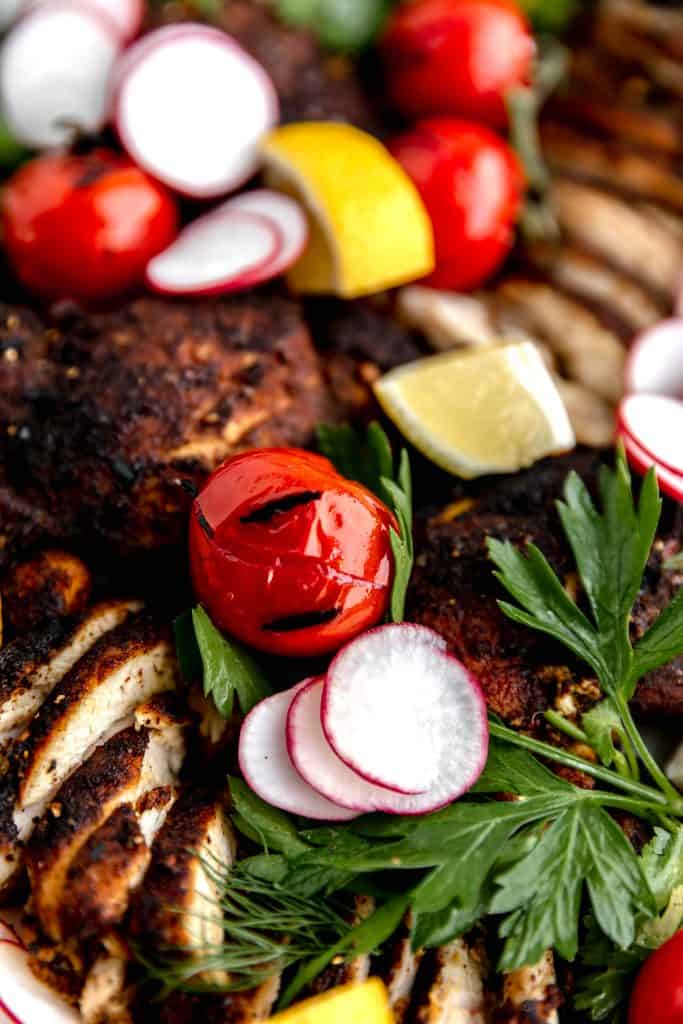 close up of grilled tomatoes with radishes, lemons and chicken