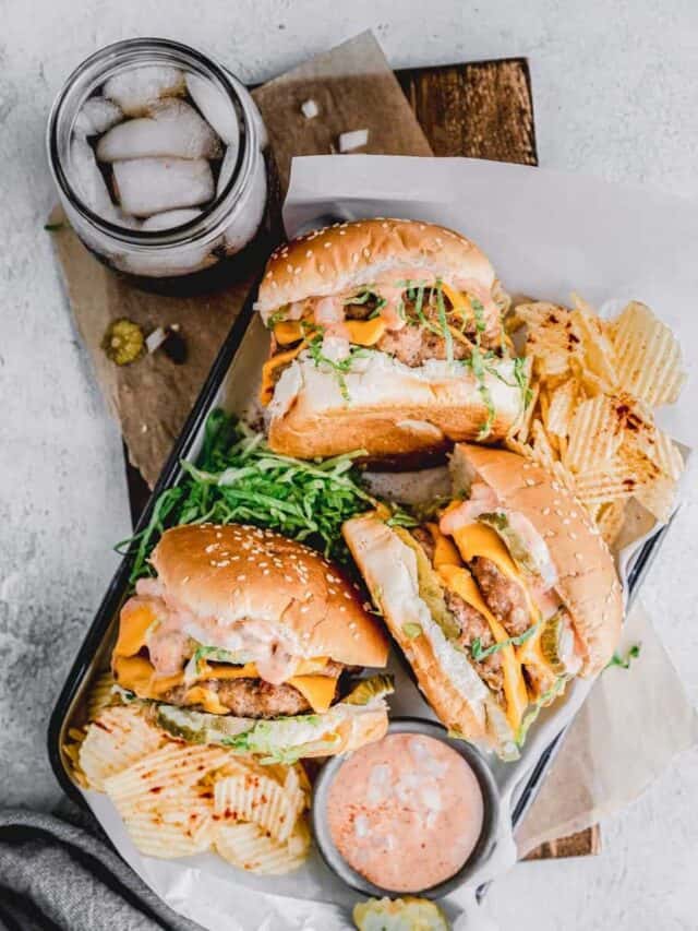 pork burgers on a tray with all the ingredients and chips