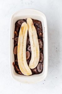 2 slices of bananas over the top of the chocolate chips on top of the chocolate banana bread batter
