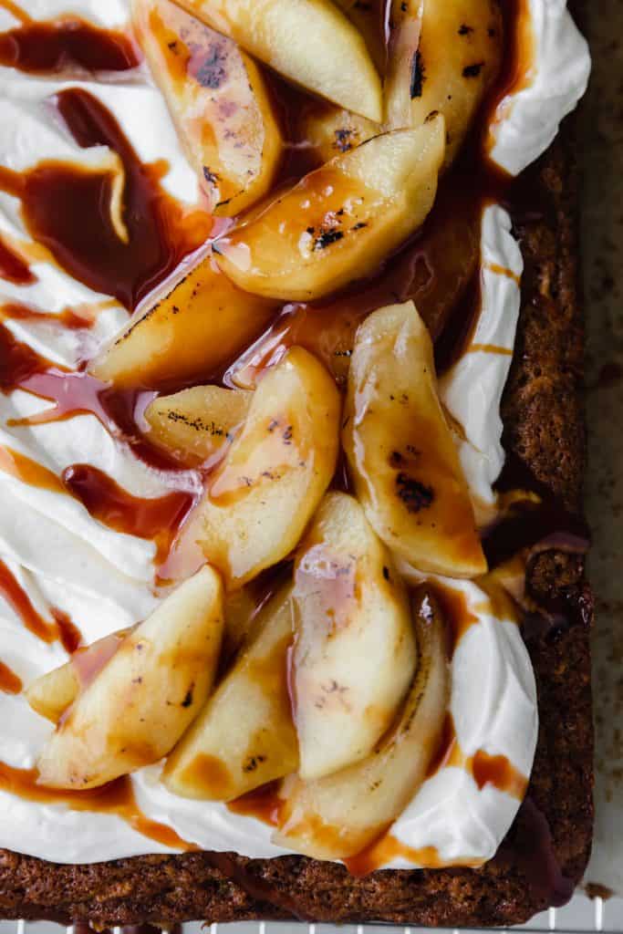 apple cake topped with frosting, bruleed apples and drenched in caramel