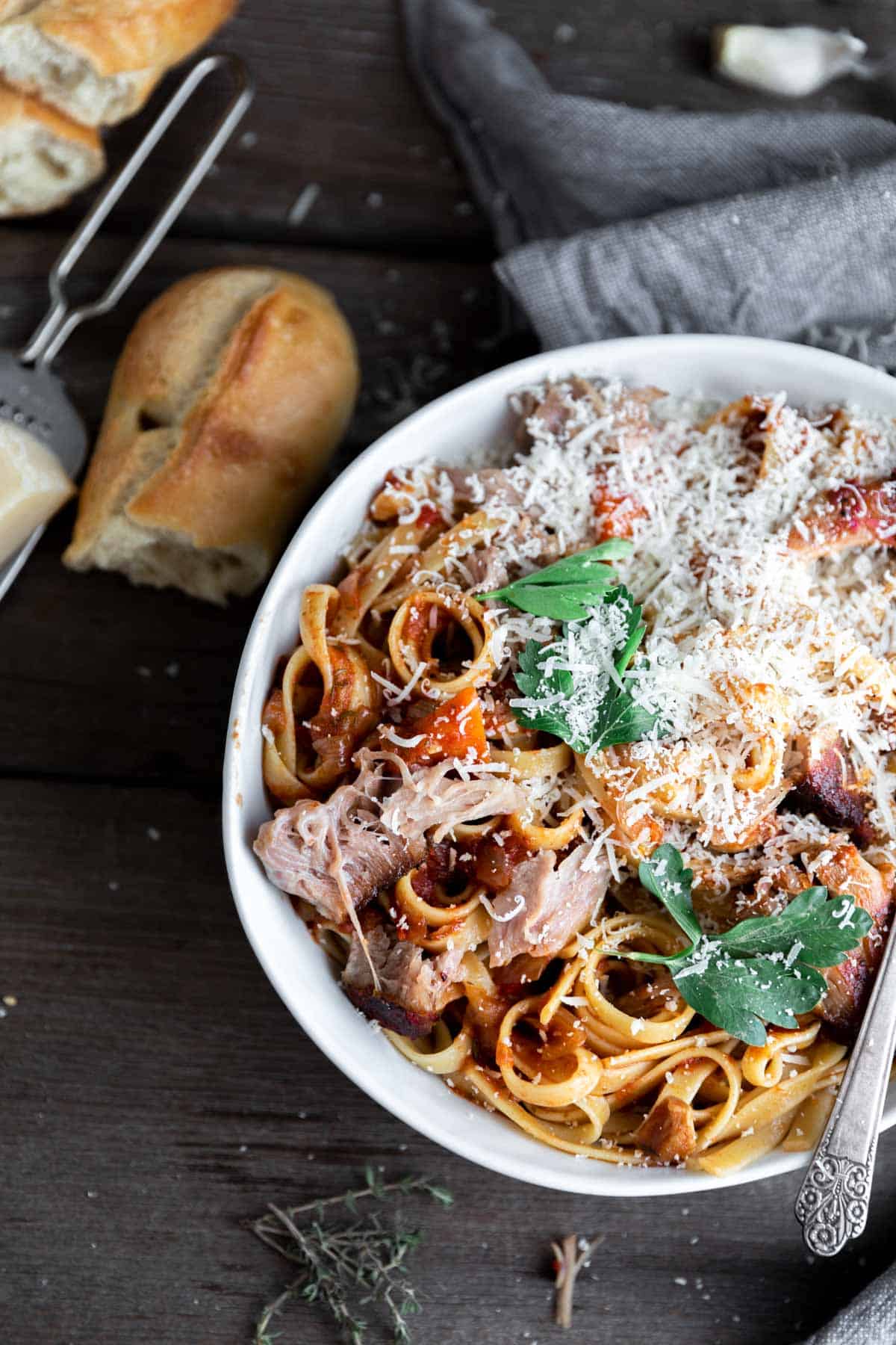 Pork Sugo mixed with fettuccini noodles, parmesan cheese and basil in a bowl.