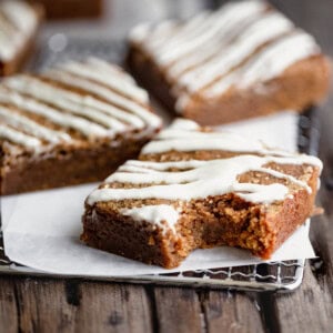 Molasses Blondies drizzled with white chocolate and cut into squares with a bite taken out of one.