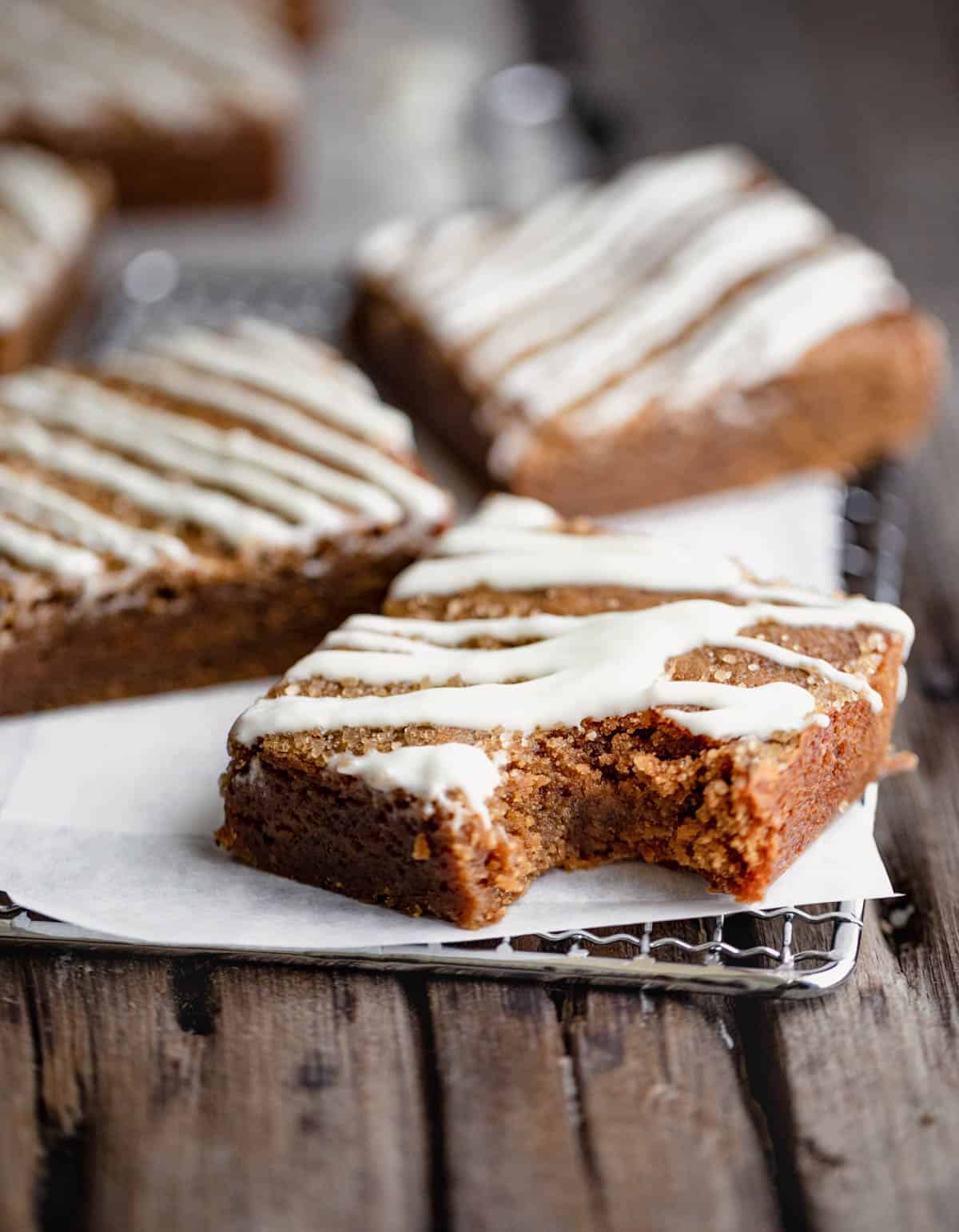 Molasses Blondies drizzled with white chocolate and cut into squares with a bite taken out of one. 