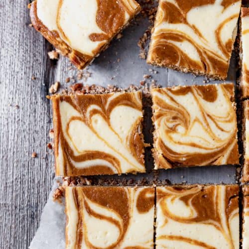 pumpkin swirl cheesecake bars cut into squares on top of parchment paper