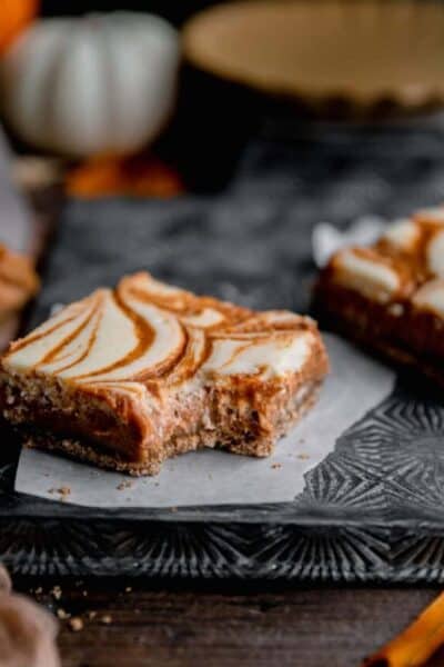 Pumpkin swirl cheesecake bar with a bite taken out of it.