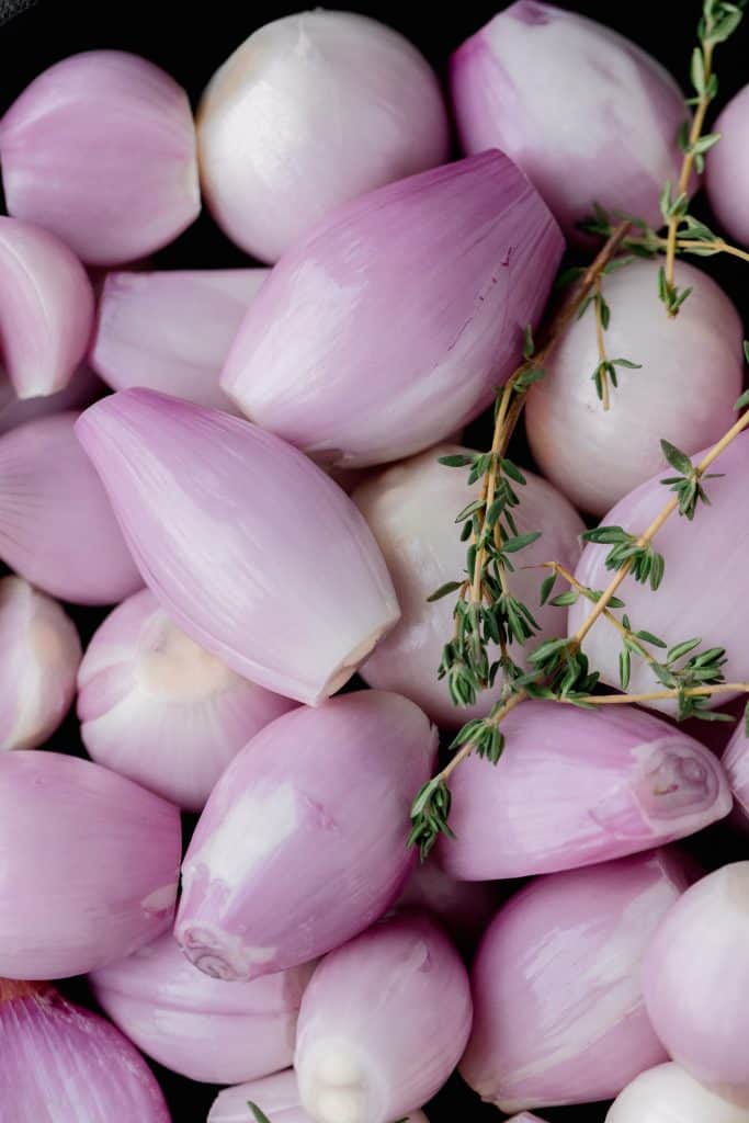 peeled purple shallots with thyme sprigs