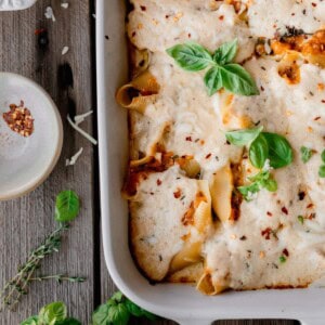 Pumpkin Cheese Stuffed Shells in a baking dish topped with fresh basil.