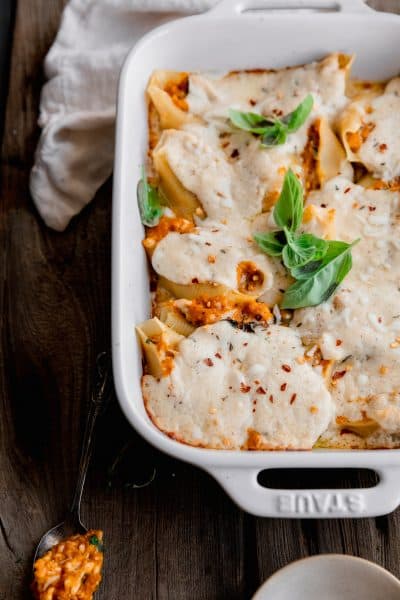 pumpkin stuffed shells topped with fresh basil in a white ceramic dish