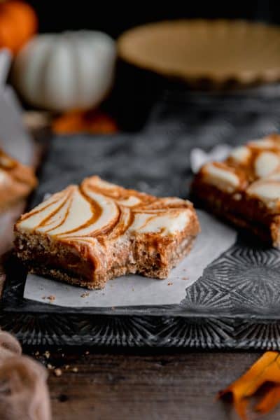 Pumpkin swirl cheesecake bar with a bite taken out of it.