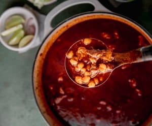 a pot of pozole rojo with a ladle lifted out of the pot