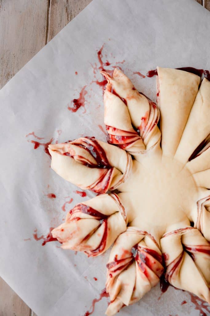 raw dough filled with raspberry filling being twisted into points