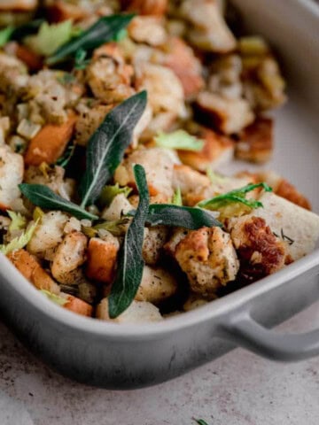 Traditional Bread Stuffing topped with sage in a baking dish.
