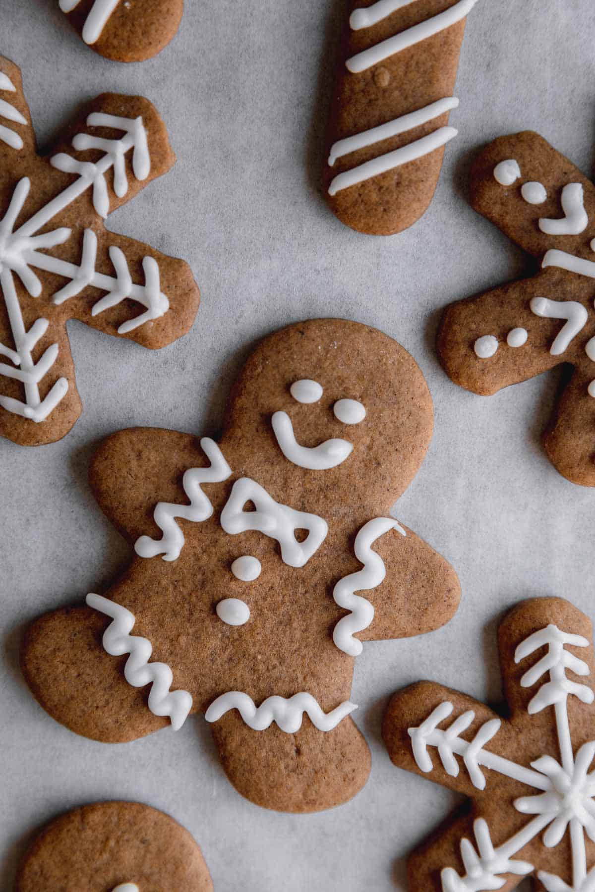 Gingerbread man cookie surrounded by snowflake and candy cane shaped gingerbread cookies. 
