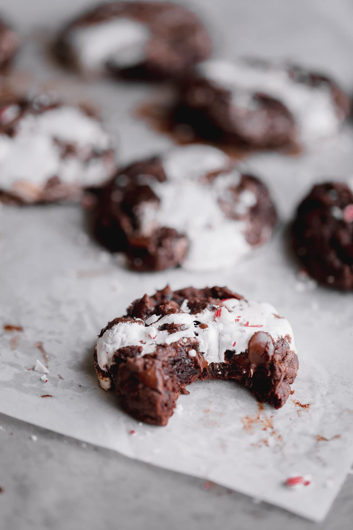 Hot Chocolate Cookies topped with gooey marshmallow, crushed candy cane and a bite taken out.