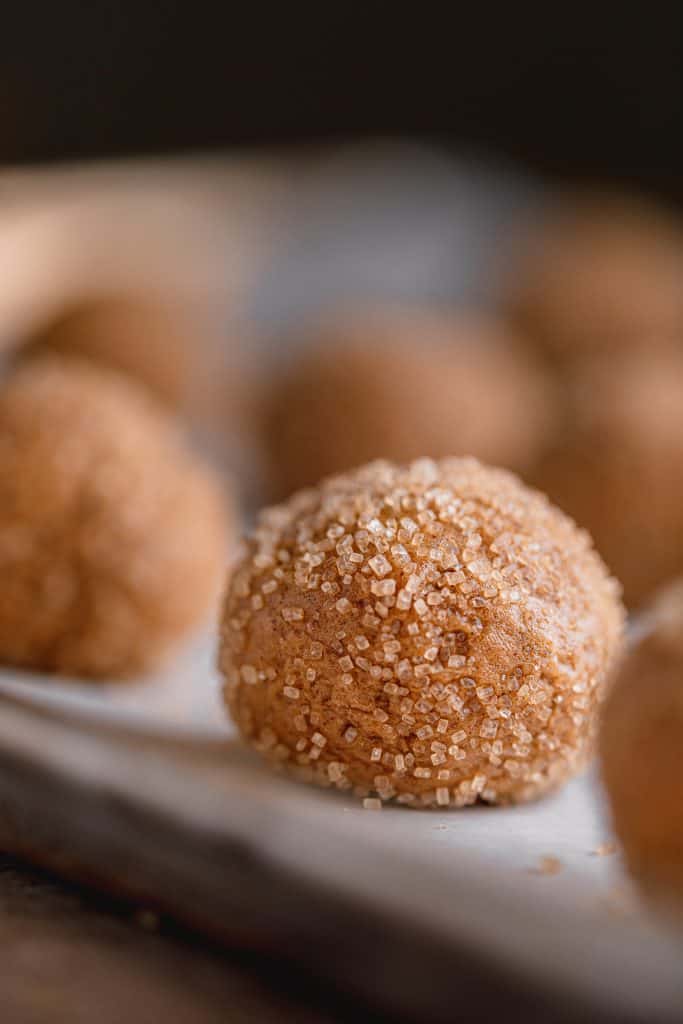 soft molasses cookie dough balls rolled in sugar and lined on a tray