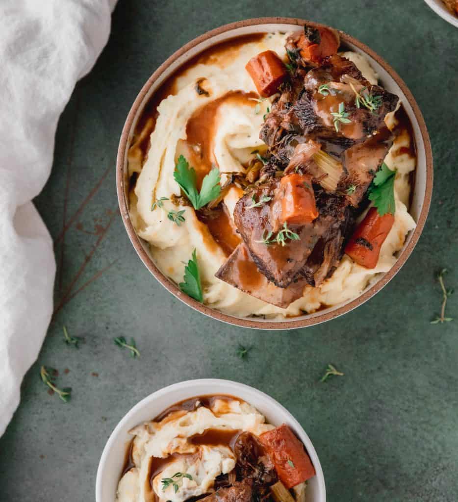 a bowl of mashed potatoes topped with short rib