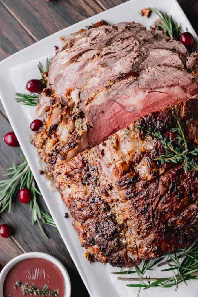 sliced beef on a platter with rosemary and cranberries