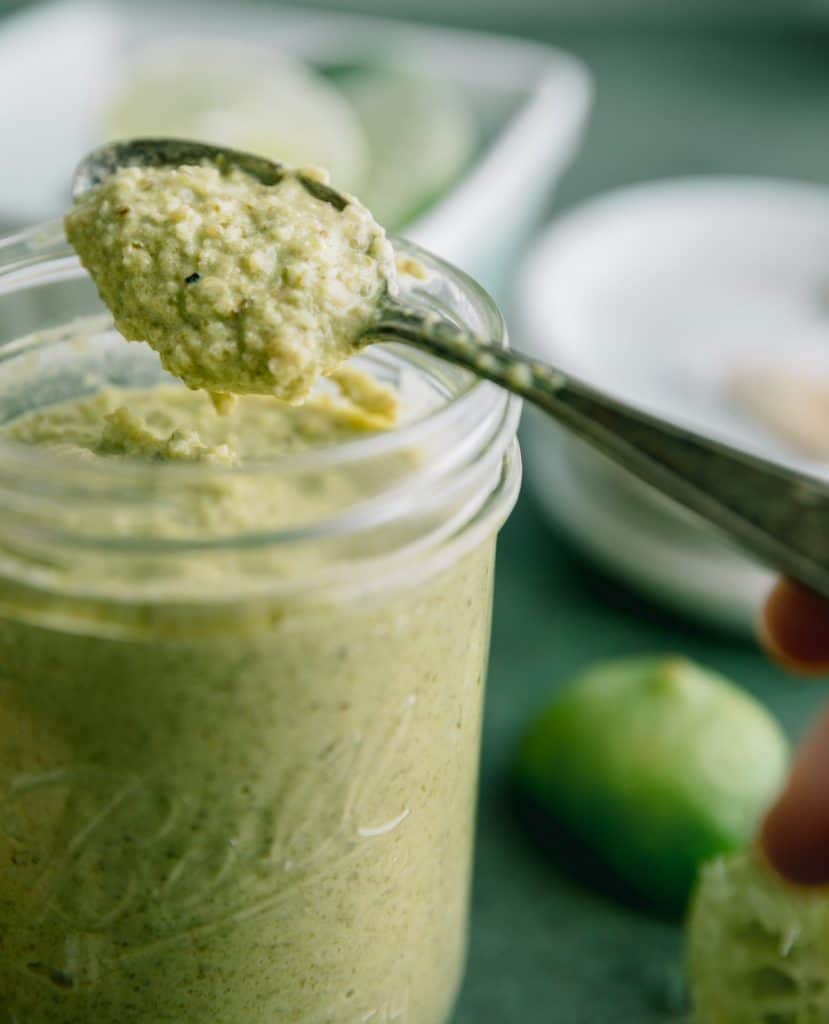 creamy taco truck green salsa on a spoon over a jar of it