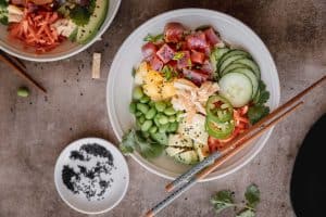 poke bowl with tuna, veggies and pineapple in a bowl with chop sticks across