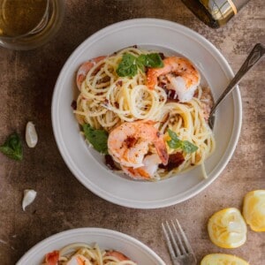 Shrimp pasta with lemon and crispy prosciutto in a bowl with a fork.