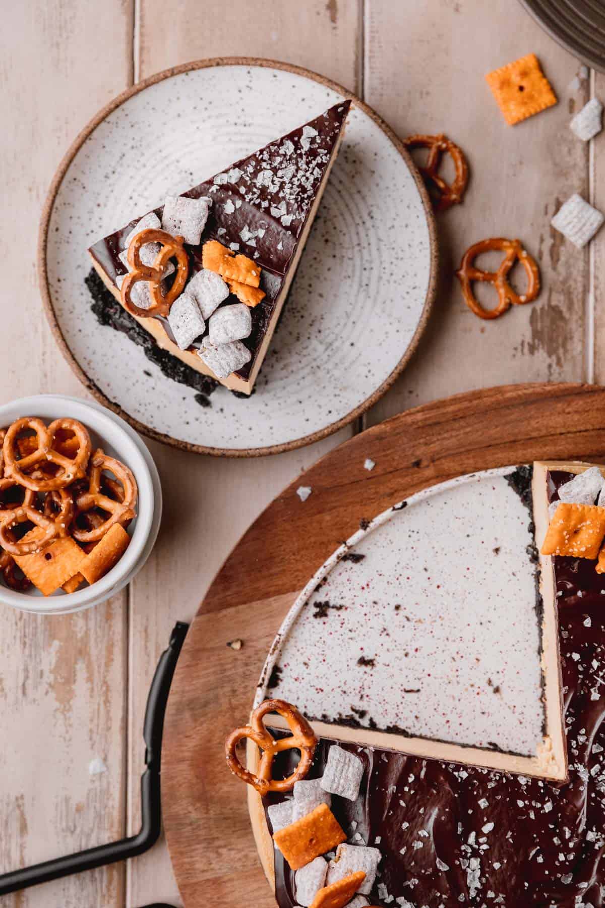 A slice of Chocolate Peanut Butter Cheesecake on a plate next to the whole cheesecake.