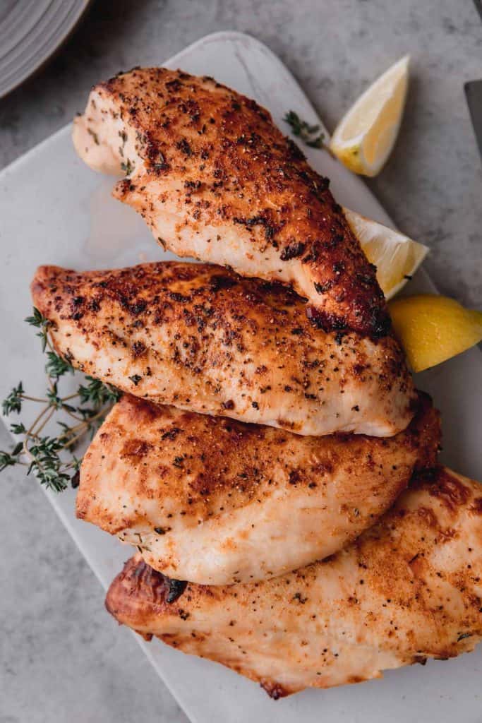 4 juicy air fryer chicken breast with thyme and lemon wedges