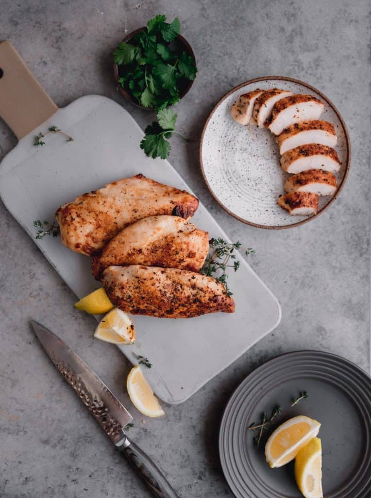 sliced air fryer chicken breast next to whole pieces