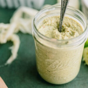Creamy Taco Truck Green Salsa in a glass jar with a spoon.